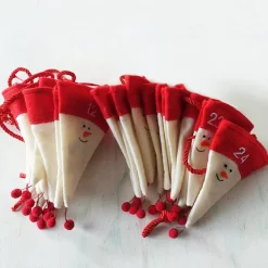 Adventskalender aus Filzmützen mit stilisiertem Schneemann-Gesicht