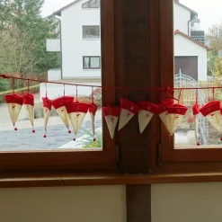 Adventskalender aus Filzmützen mit stilisiertem Schneemann-Gesicht