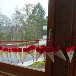 Adventskalender aus Filzmützen mit stilisiertem Schneemann-Gesicht