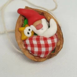 Baumschmuck Walnussschale Schaukelbettchen mit kleinem schlafend Wichtel mit roter Zipfelmütze und kleinem Stern