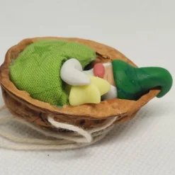 Baumschmuck Walnussschale Schaukelbettchen mit kleinem schlafend Wichtel mit Zipfelmütze und nachtleuchtendem Stern