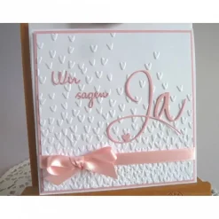 Einladungskarte zur Hochzeit in weiß/rosa, mit geprägtem Hintergrund, und *Wir sagen Ja* Schriftzug