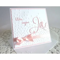 Einladungskarte zur Hochzeit in weiß/rosa, mit geprägtem Hintergrund, und *Wir sagen Ja* Schriftzug