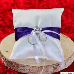 Elegantes Ringkissen aus weißem Satin mit lilanem Satinband und zarter weißer Schleife - Perfekte Hochzeitsdekoration