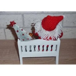 gehäkelter Weihnachtsmann mit Geschenken auf einer Holzbank