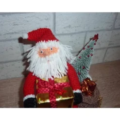 gehäkelter Weihnachtsmann mit Geschenken auf einer Holzbank