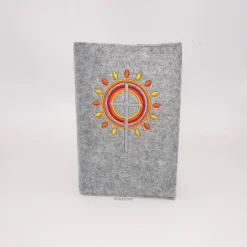 Gotteslobhülle, Filz, grau, bestickt mit grauem Kreuz, mit orangen, gelben Strahlen, die wie eine Blume angeordnet sind