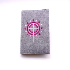 Gotteslobhülle, Filz, grau, bestickt mit grauem Kreuz, rosa + dunkelroten Strahen, die wie eine Blume angeordnet sind