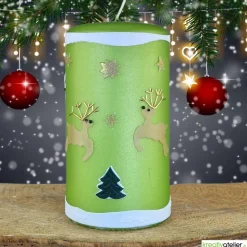 grüne Weihnachtskerze mit Rentieren, Tannen und Sternen