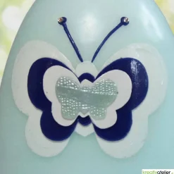 große Ostereikerze in hellblau mit Schmetterling in blau-weißem Verzierwachs