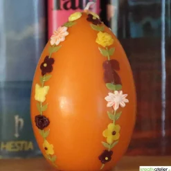 große Ostereikerze in orange mit doppelter, frühlingshafter Blumenranke verziert, Osterdeko, Ostergeschenk
