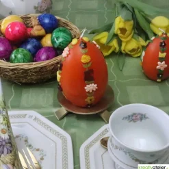 große Ostereikerze in orange mit doppelter, frühlingshafter Blumenranke verziert, Osterdeko, Ostergeschenk