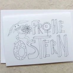 Karte zum Ausmalen, FROHE OSTERN und Hase mit Blumenstrauß, schwarz-weiß, Klappkarte DinA 6, mit weißem Umschlag.