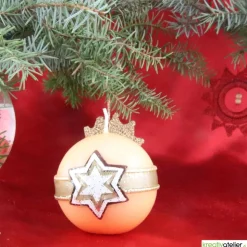 Orangene Weihnachtskerze mit waagerechtem Wachsband und Stern aus mehreren Wachslagen