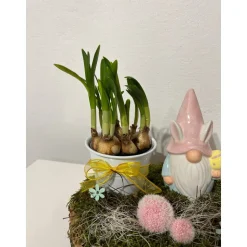 Osterdeko auf einer Baumscheibe mit Blumentopf und einem Wichtel