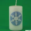 Zauberhaftes Lichtspiel für die Wintermonate: Winterkerze mit Eiskristall / Schneeflocke auf blauem Himmel