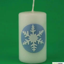 Zauberhaftes Lichtspiel für die Wintermonate: Winterkerze mit Eiskristall / Schneeflocke auf blauem Himmel