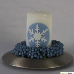 Zauberhaftes Lichtspiel für die Wintermonate: Winterkerze mit Eiskristall / Schneeflocke auf blauem Himmel