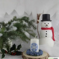 Zauberhaftes Lichtspiel für die Wintermonate: Winterkerze mit Eiskristall / Schneeflocke auf blauem Himmel